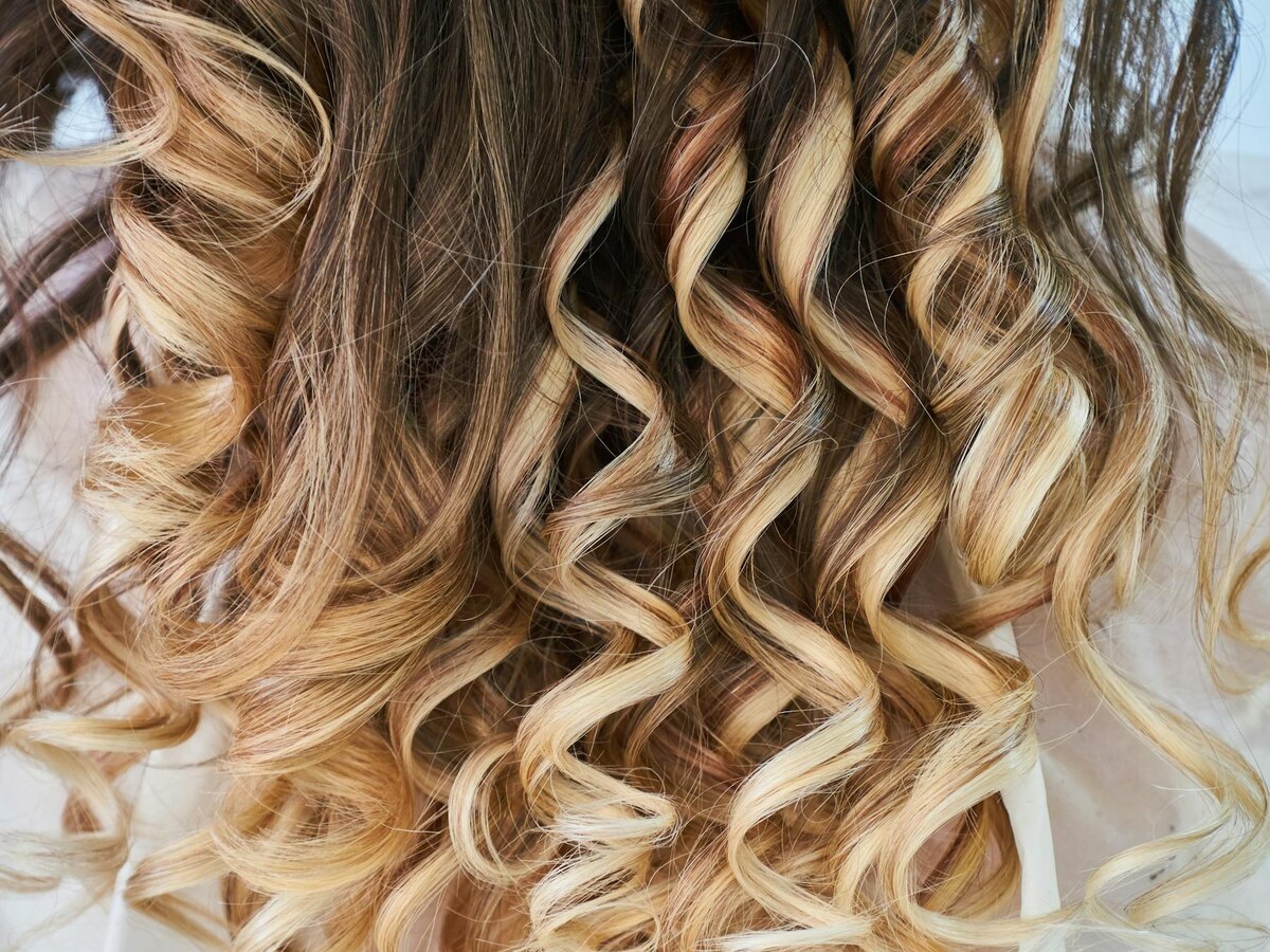 Close-up of honey balayage curls with glossy finish